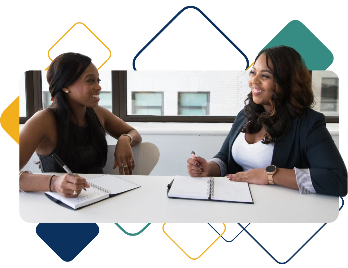 Two-business-women-conversing-at-office-table 1
